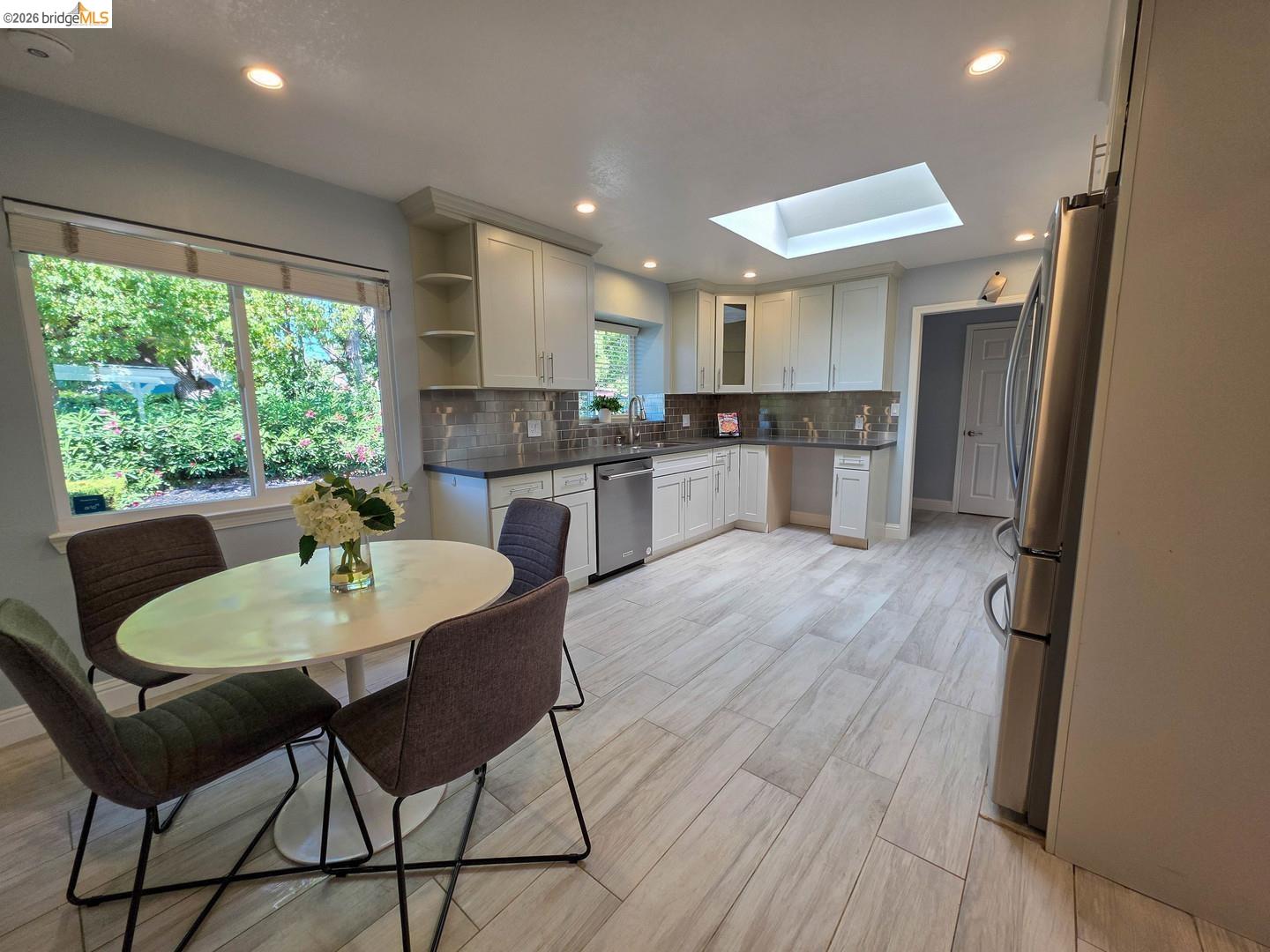 965 Springer Road Los Altos, CA 94024 - Photo 13 of 31 Well-appointed kitchen featuring light-toned cabinetry, dark countertops, a tiled backsplash, stainless steel appliances, and a skylight