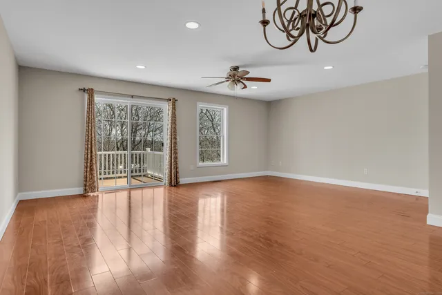 a view of an empty room with glass door and wooden floor