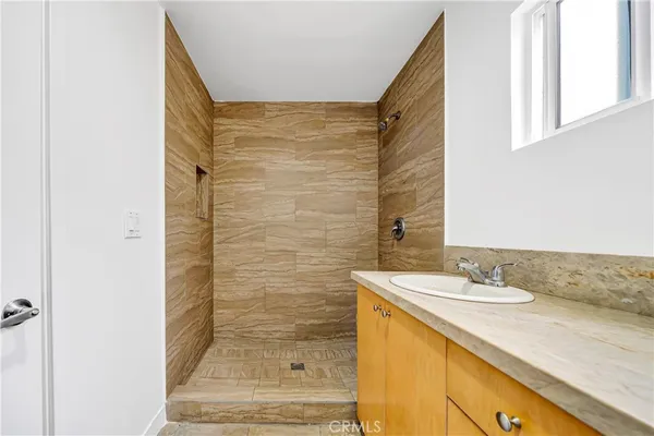 a bathroom with a granite countertop sink a mirror and shower