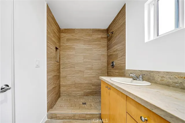 a bathroom with a granite countertop sink a mirror and shower