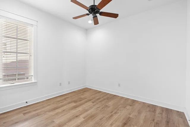 an empty room with a window and a fan