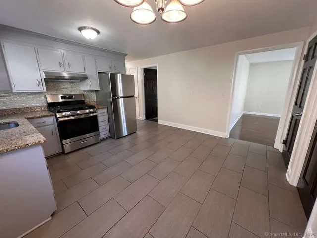 a kitchen with stainless steel appliances granite countertop a refrigerator and a stove top oven
