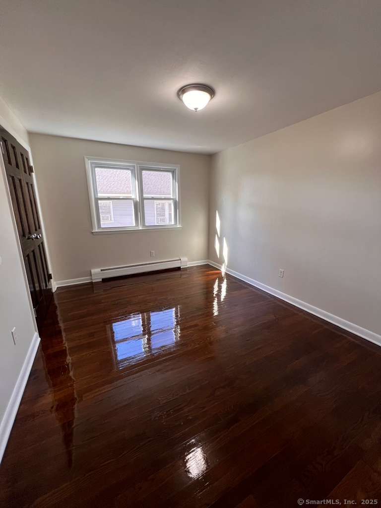 193 City View Avenue Bridgeport, CT 06606 - Photo 10 of 16 an empty room with wooden floor and windows