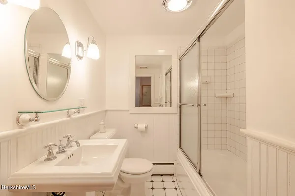 a bathroom with a sink a toilet and shower a mirror