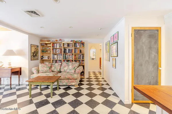 a living room with a black white checkered floor with a gaming machine and dining table