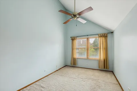 an empty room with chandelier fan and windows