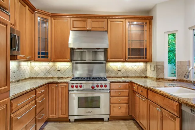 a kitchen with granite countertop stainless steel appliances a stove sink and cabinets