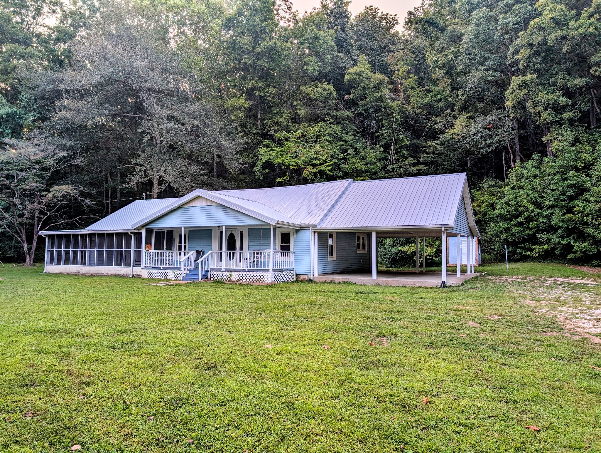 a view of a house next to a big yard with large trees