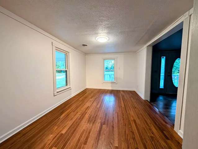a view of an empty room with wooden floor and a ceiling fan