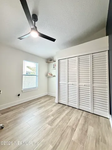 a view of empty room with wooden floor and fan