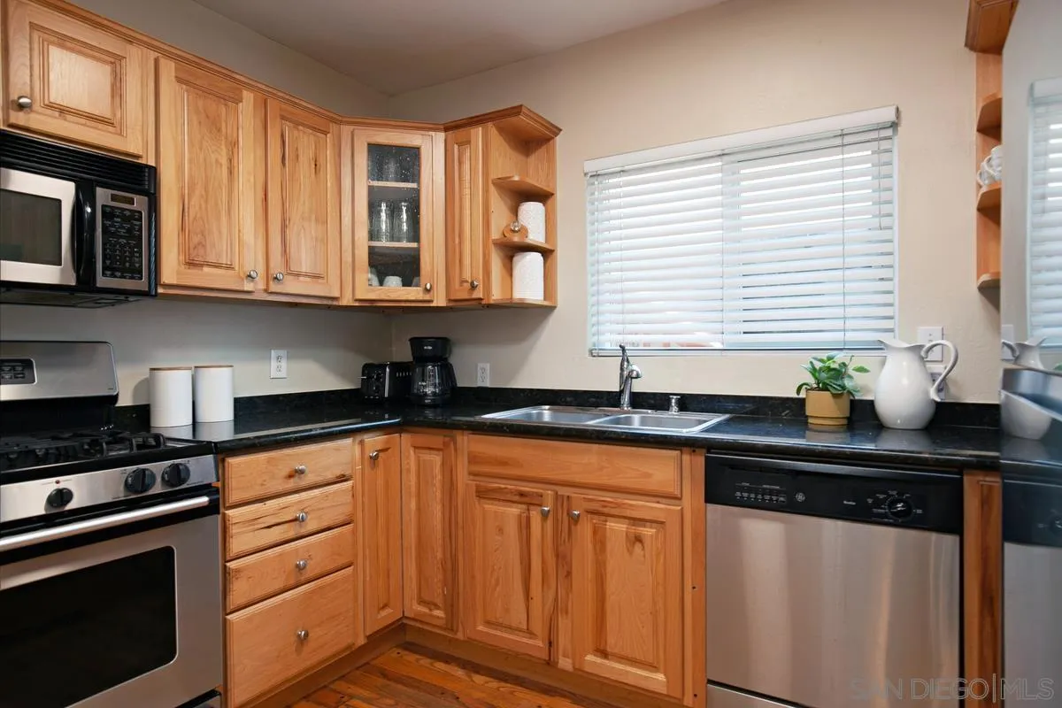 3973 8th Avenue San Diego, CA 92103 - Photo 8 of 21 a kitchen with granite countertop white cabinets and black appliances