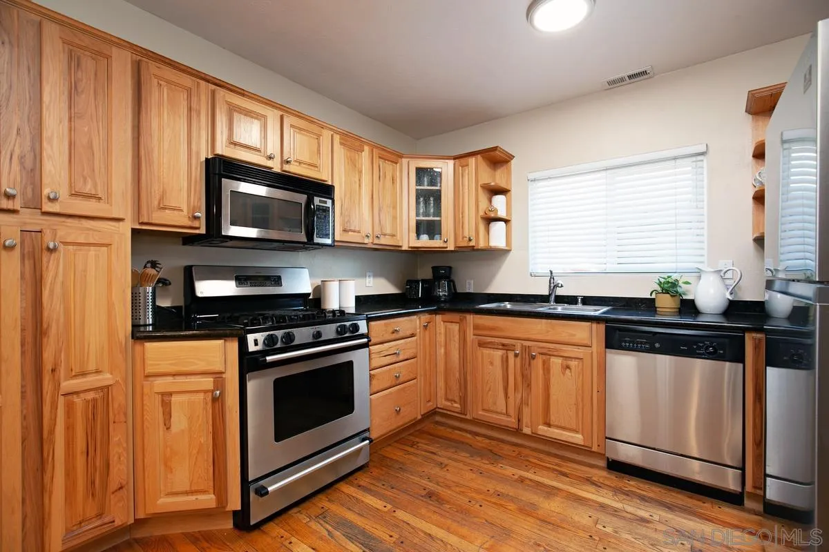 3973 8th Avenue San Diego, CA 92103 - Photo 9 of 21 a kitchen with stainless steel appliances granite countertop a stove a sink and a microwave