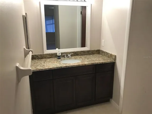 a bathroom with a granite countertop sink and a mirror