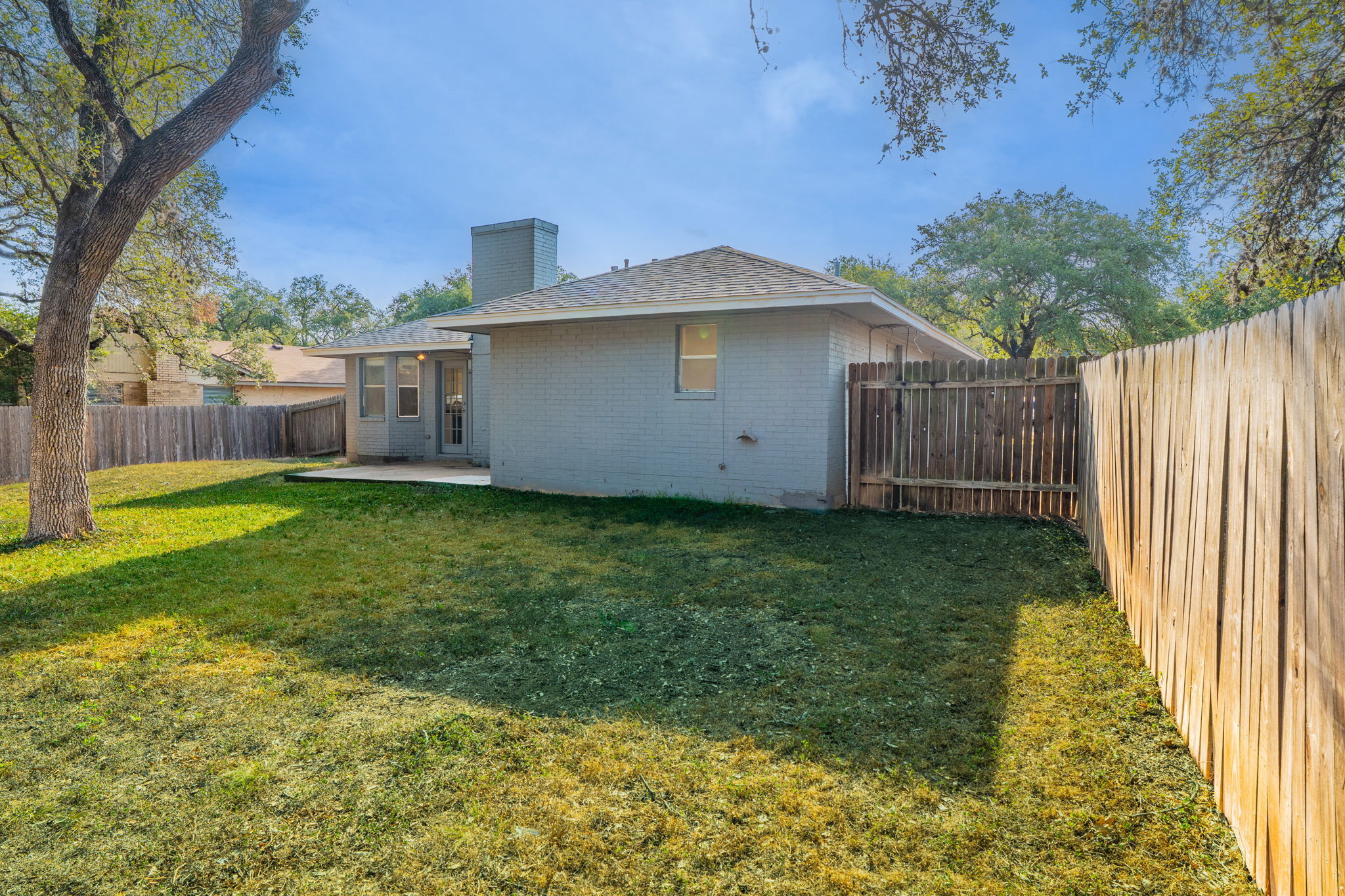 5628 Wagon Train Road Austin, TX 78749 - Photo 24 of 26 A spacious grassy lawn is fully enclosed by privacy fencing behind this classic brick home.