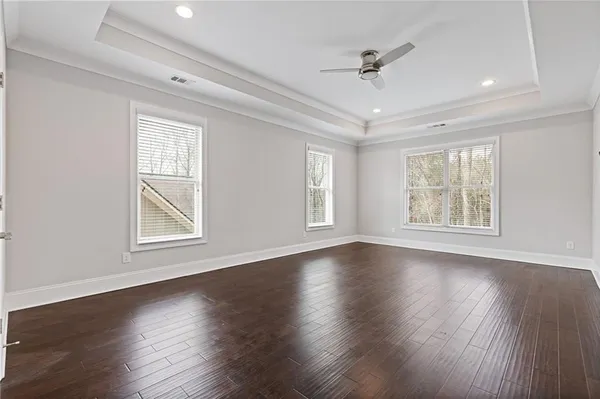 a view of an empty room with wooden floor and a ceiling fan