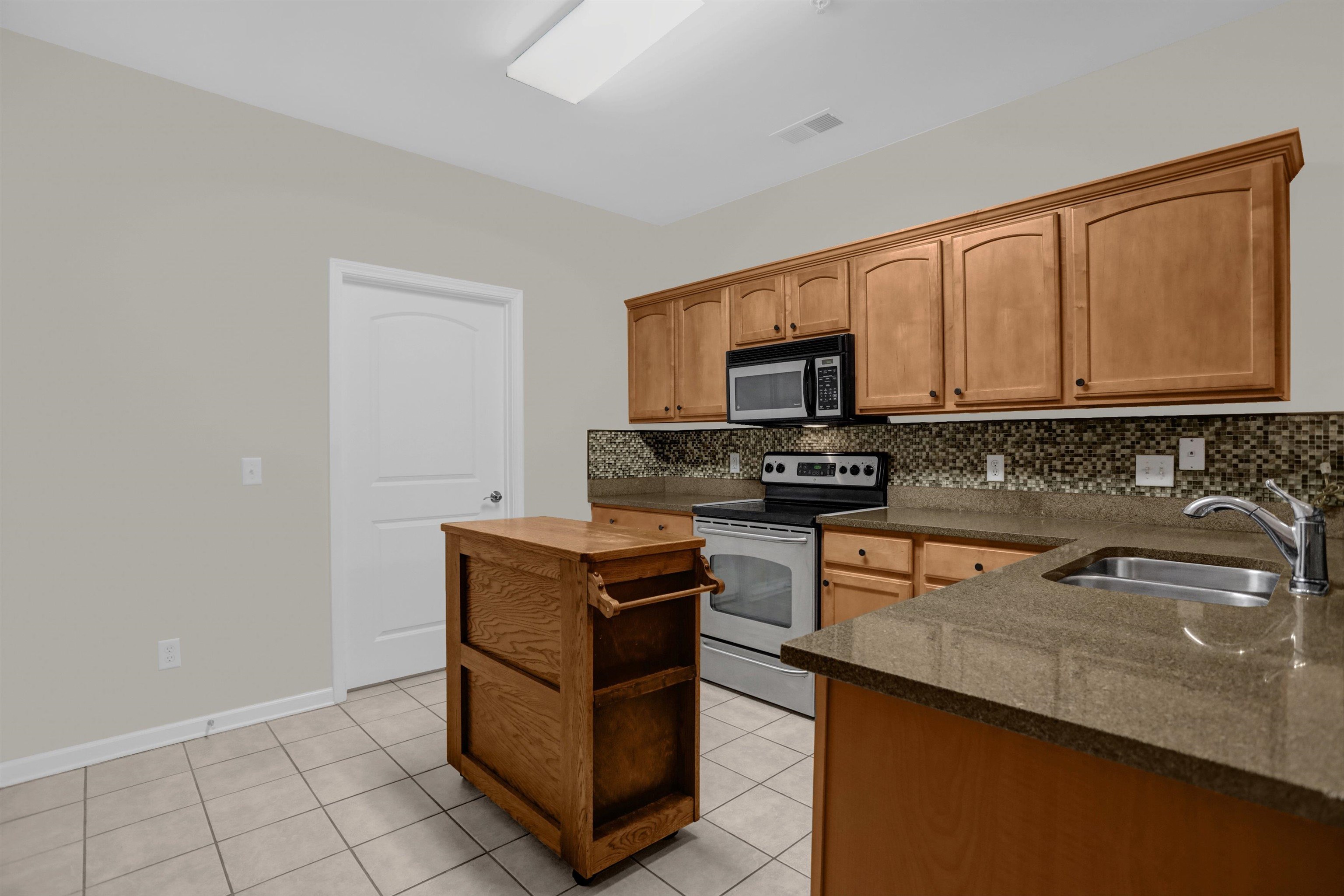 34 Peyton Ridge Drive, Unit 21 Collierville, TN 38017 - Photo 14 of 37 Kitchen featuring light wood cabinetry, stone-look countertops, stainless steel appliances, a mosaic tile backsplash, and tile flooring