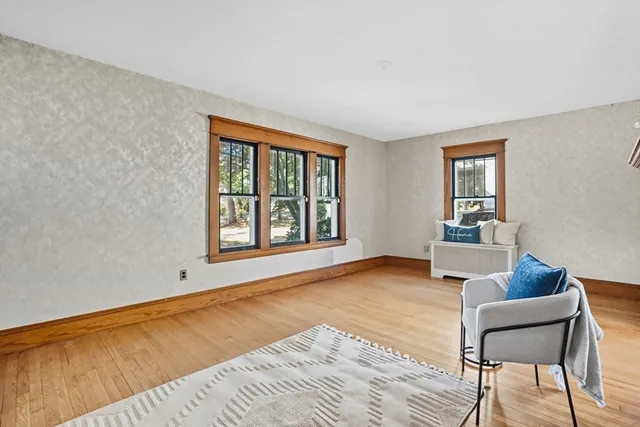 a view of an empty room with window and wooden floor