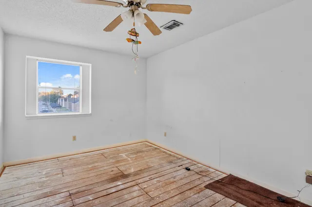 a view of a room with wooden floor and a ceiling fan