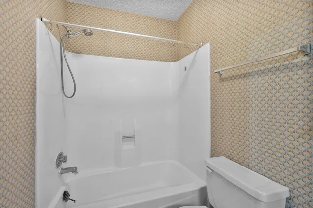 a spacious bathroom with a granite countertop sink a toilet a shower and a mirror