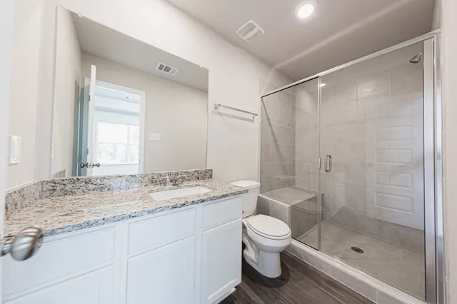 a bathroom with a granite countertop sink a toilet and shower