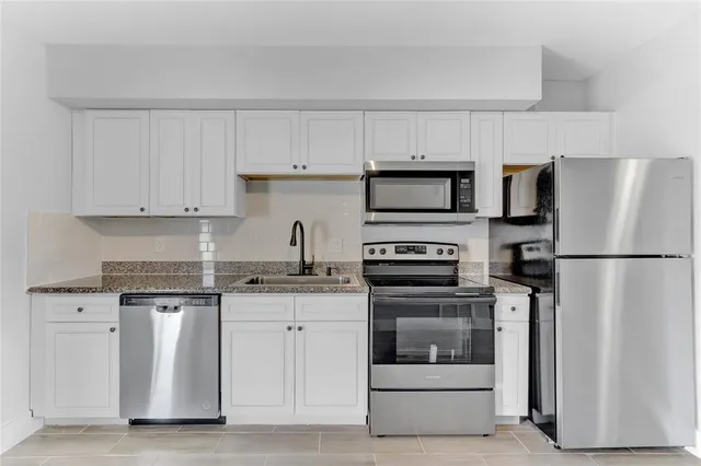 a kitchen with white cabinets and stainless steel appliances