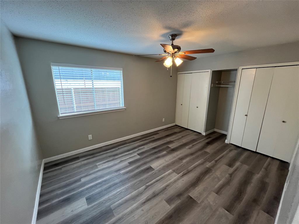 1413 Ridgecrest Drive Plano, TX 75074 - Photo 14 of 22 Unfurnished bedroom featuring multiple closets, a textured ceiling, a ceiling fan, and dark wood-style flooring