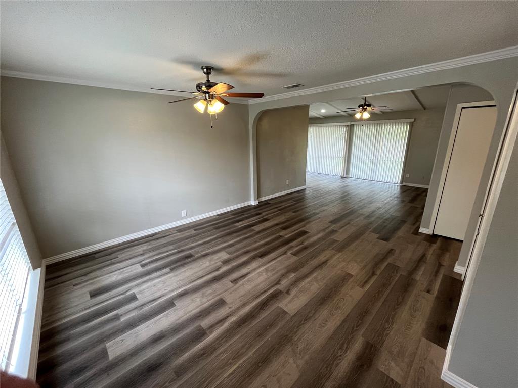 1413 Ridgecrest Drive Plano, TX 75074 - Photo 4 of 22 Spare room with arched walkways, a ceiling fan, dark wood-type flooring, a textured ceiling, and ornamental molding