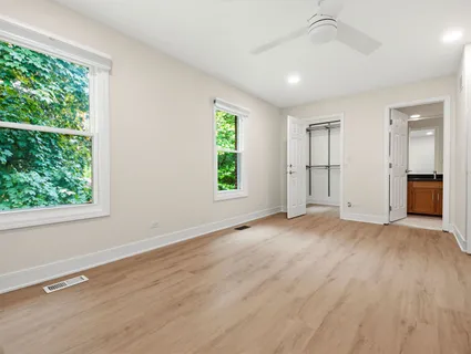 an empty room with wooden floor cabinet and windows