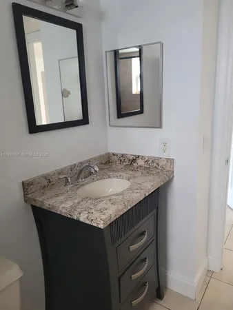 a bathroom with a granite countertop sink and a mirror