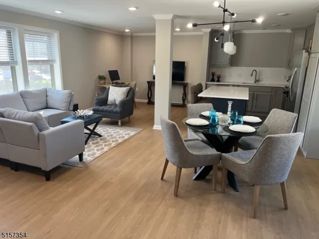 a living room with furniture kitchen view and a wooden floor