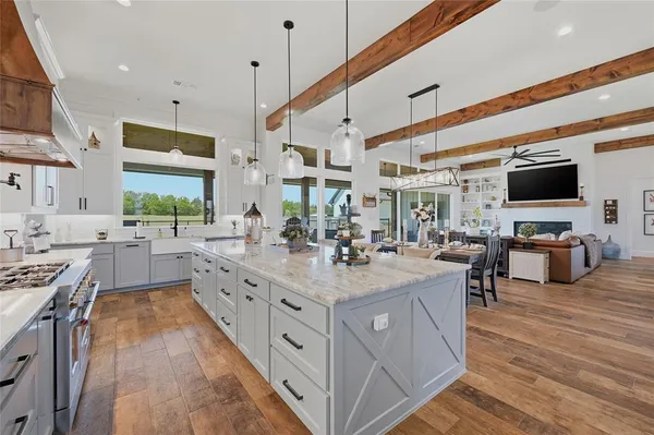 a large kitchen with stainless steel appliances a stove center island a oven a dining table and chairs with wooden floor