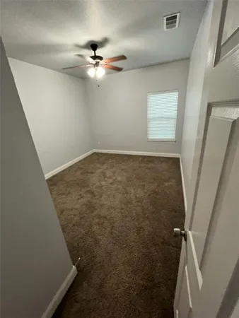 an empty room with a chandelier fan and windows