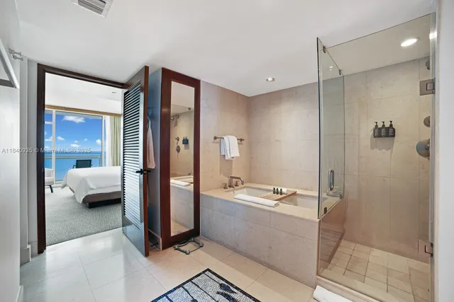a en suite spacious bathroom with a tub shower and bedroom view