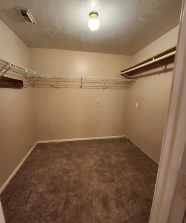 an empty room with a chandelier fan and closet