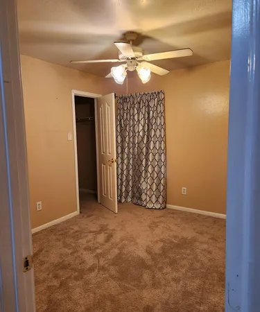 a view of an empty room with a chandelier fan