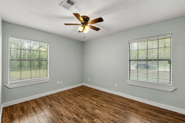 a view of empty room with wooden floor and fan