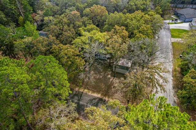 an aerial view of residential house with outdoor space and trees all around