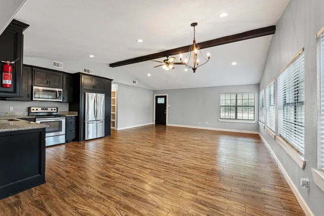 a view of an empty room with kitchen appliances and a window
