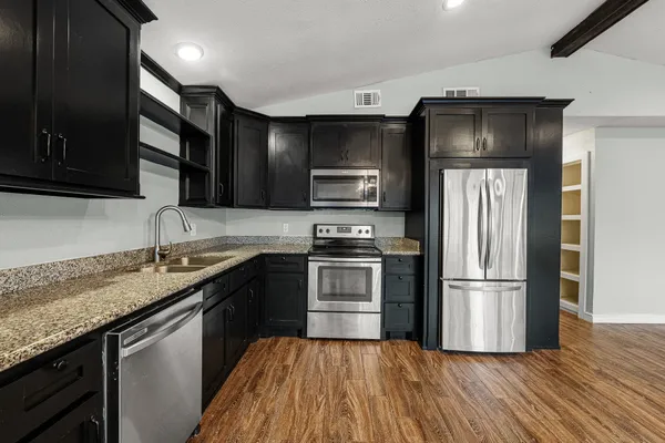 a kitchen with stainless steel appliances granite countertop a stove a sink and a refrigerator