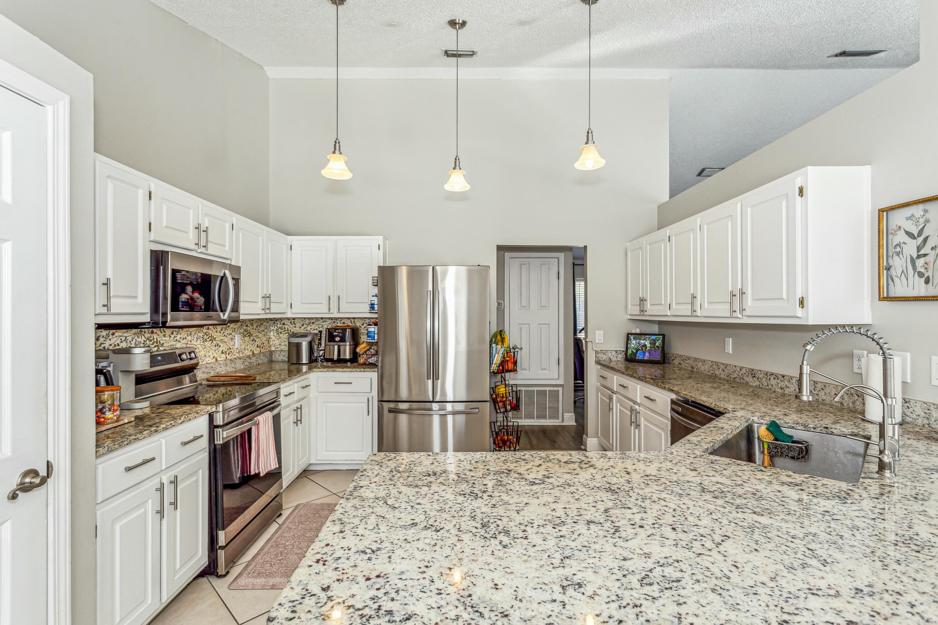 4741 Coronado Circle Crestview, FL 32539 - Photo 12 of 35 a kitchen with stainless steel appliances granite countertop a refrigerator a stove a sink dishwasher a refrigerator and white cabinets with wooden floor