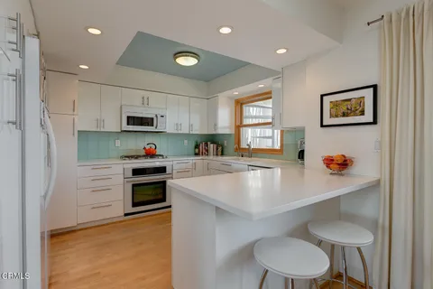 a kitchen with stainless steel appliances a white refrigerator cabinets a stove a sink and a window