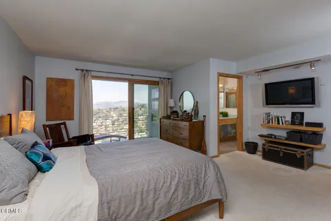a bedroom with a bed and a flat tv screen on dresser