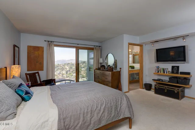 a bedroom with a bed and a flat tv screen on dresser