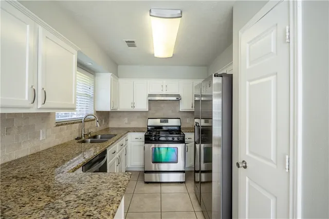a kitchen with granite countertop a sink and cabinets