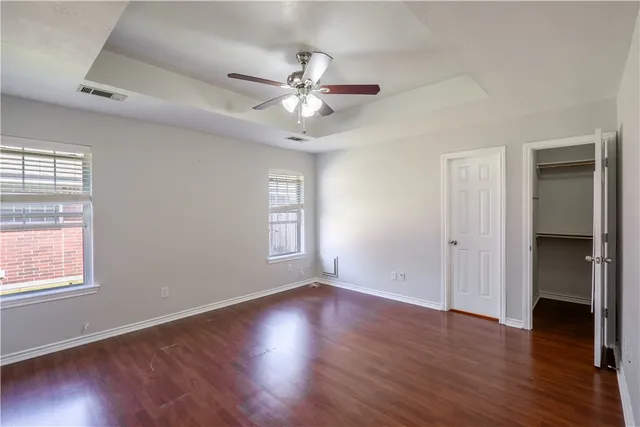 an empty room with wooden floor and ceiling fan