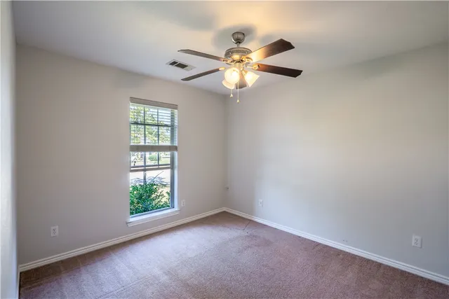 an empty room with windows and fan
