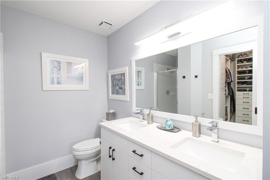 225 Robin Hood Circle, Unit 203 Naples, FL 34104 - Photo 40 of 50 Bathroom with hardwood / wood-style floors, double sink, vanity with extensive cabinet space, walk in shower, and toilet