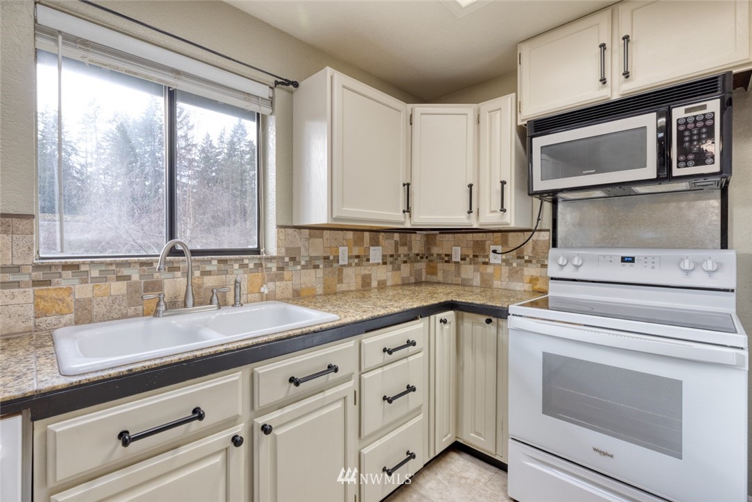 17517 48th Street East Lake Tapps, WA 98391 - Photo 11 of 36 a kitchen with granite countertop white cabinets stainless steel appliances a sink and a window