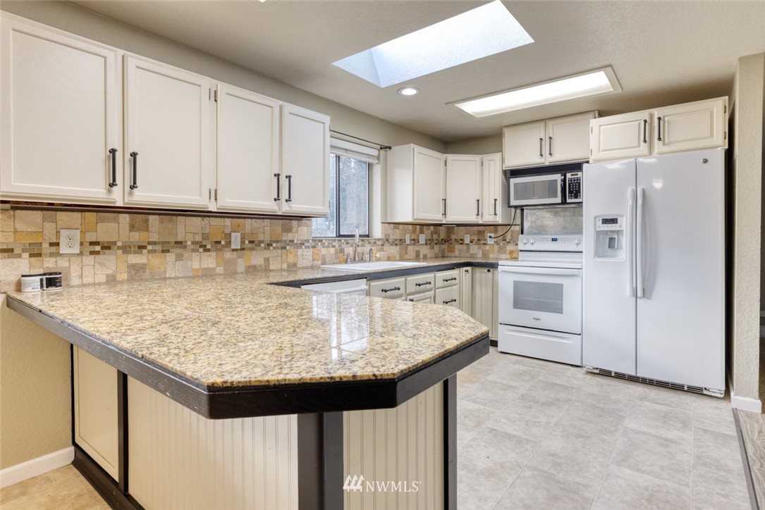 17517 48th Street East Lake Tapps, WA 98391 - Photo 8 of 36 a kitchen with stainless steel appliances granite countertop a sink stove refrigerator and cabinets