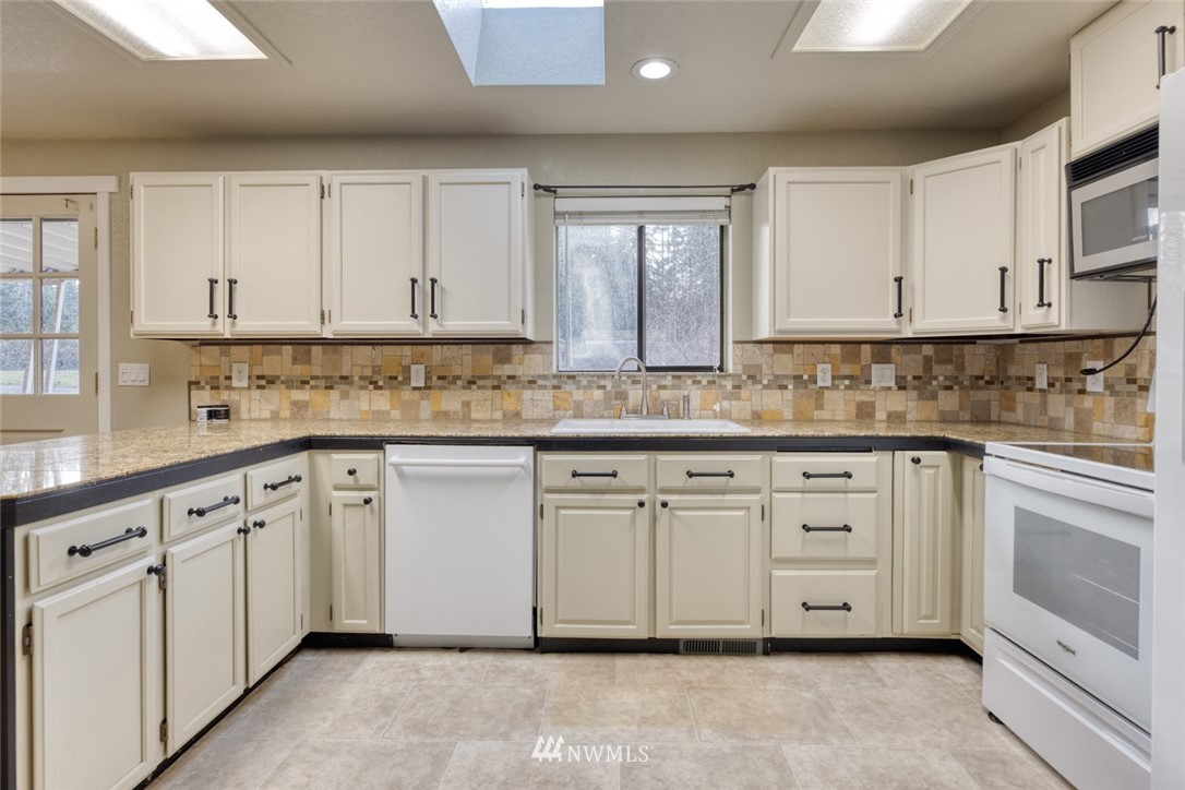 17517 48th Street East Lake Tapps, WA 98391 - Photo 10 of 36 a kitchen with granite countertop white cabinets white stainless steel appliances with a sink and dishwasher